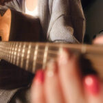 Acoustic guitar fretboard close-up showing nickel frets on a rosewood fretboard, highlighting the standard fret arrangement for acoustic guitars.