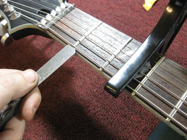 Measuring string action at the first fret with feeler gauges to determine nut height adjustment for a Floyd Rose guitar