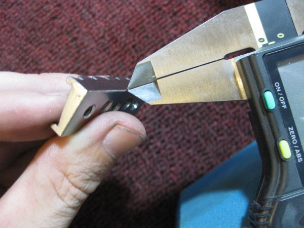 Calipers marking a precise line on a Floyd Rose nut to indicate material removal for action adjustment