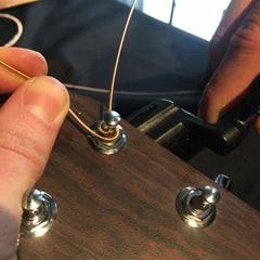 Close-up of string wraps on a tuning peg, showing new wraps below previous ones for stability.