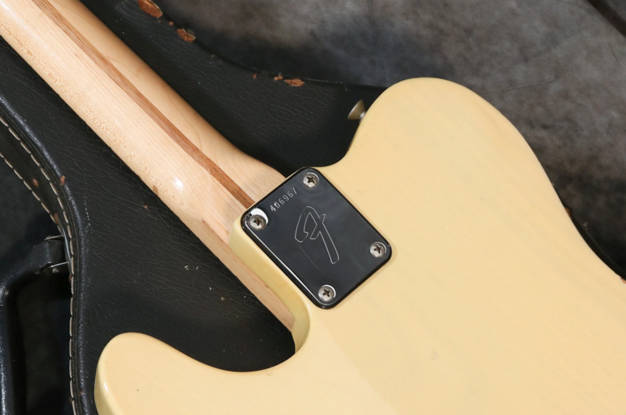 Photo of a 1973 Telecaster neck plate with an F series serial number and the distinctive 'F' logo.