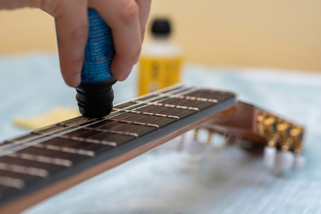 Close up of hand cleaning guitar strings with cloth