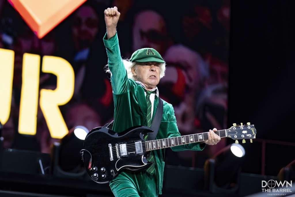 AC/DC band performing on stage, focused on Angus Young playing guitar and Brian Johnson singing.