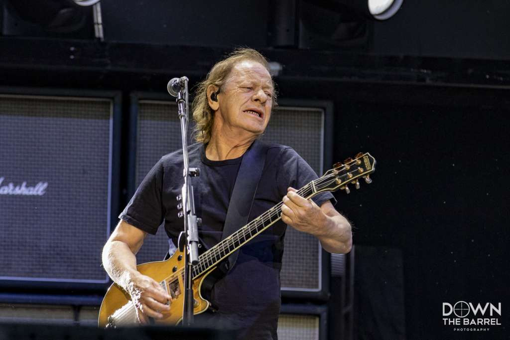 AC/DC band members performing on stage, Angus Young center stage with guitar.