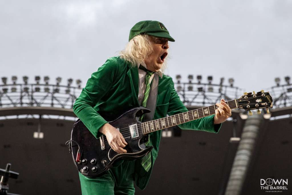 AC/DC band performing on stage, Angus Young in the foreground playing guitar.