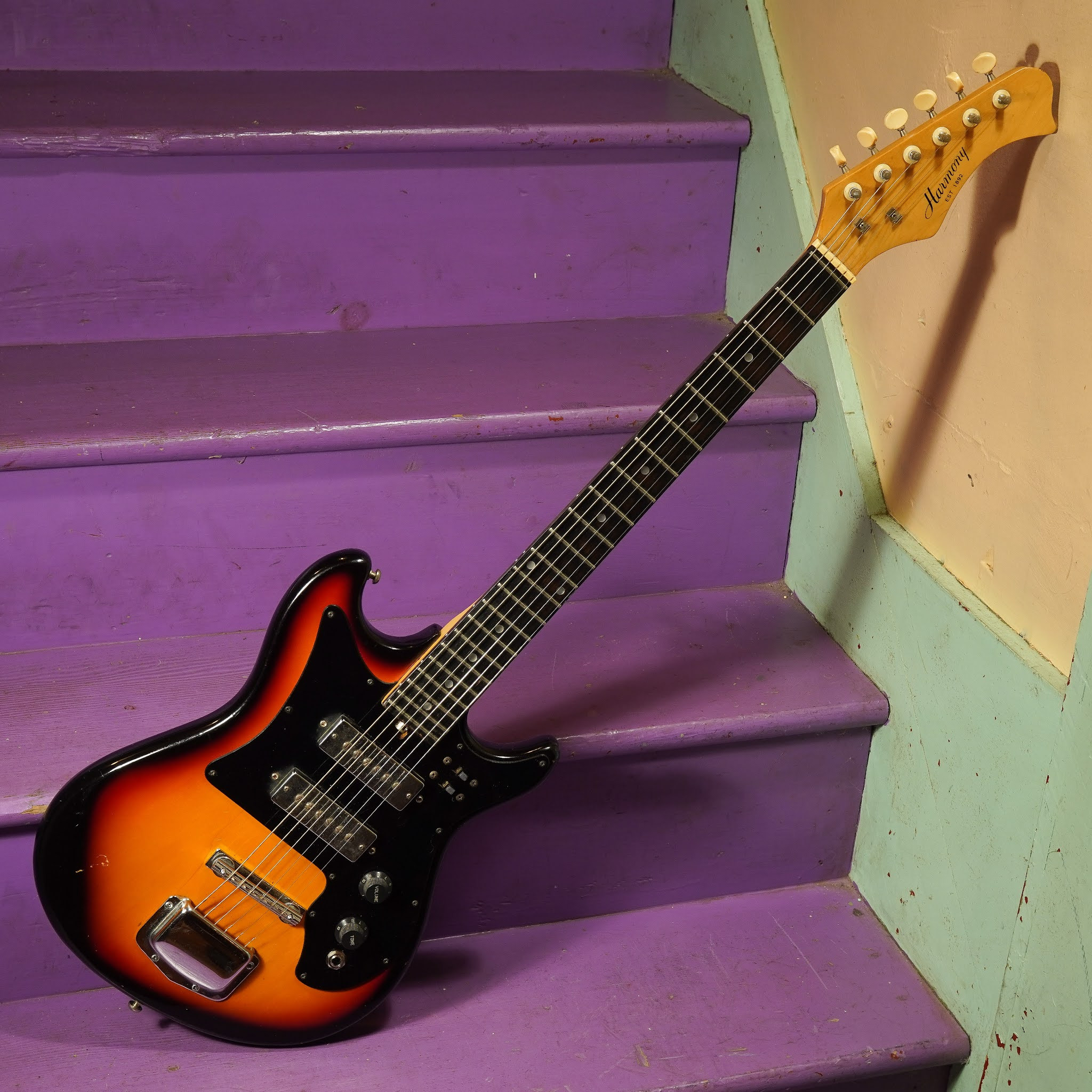 Close-up of the Harmony electric guitar headstock showcasing the Harmony logo and tuners, emphasizing the vintage aesthetic.