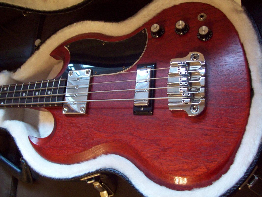 Close-up of a Gibson SG bass guitar body, highlighting the mahogany wood and SG shape.
