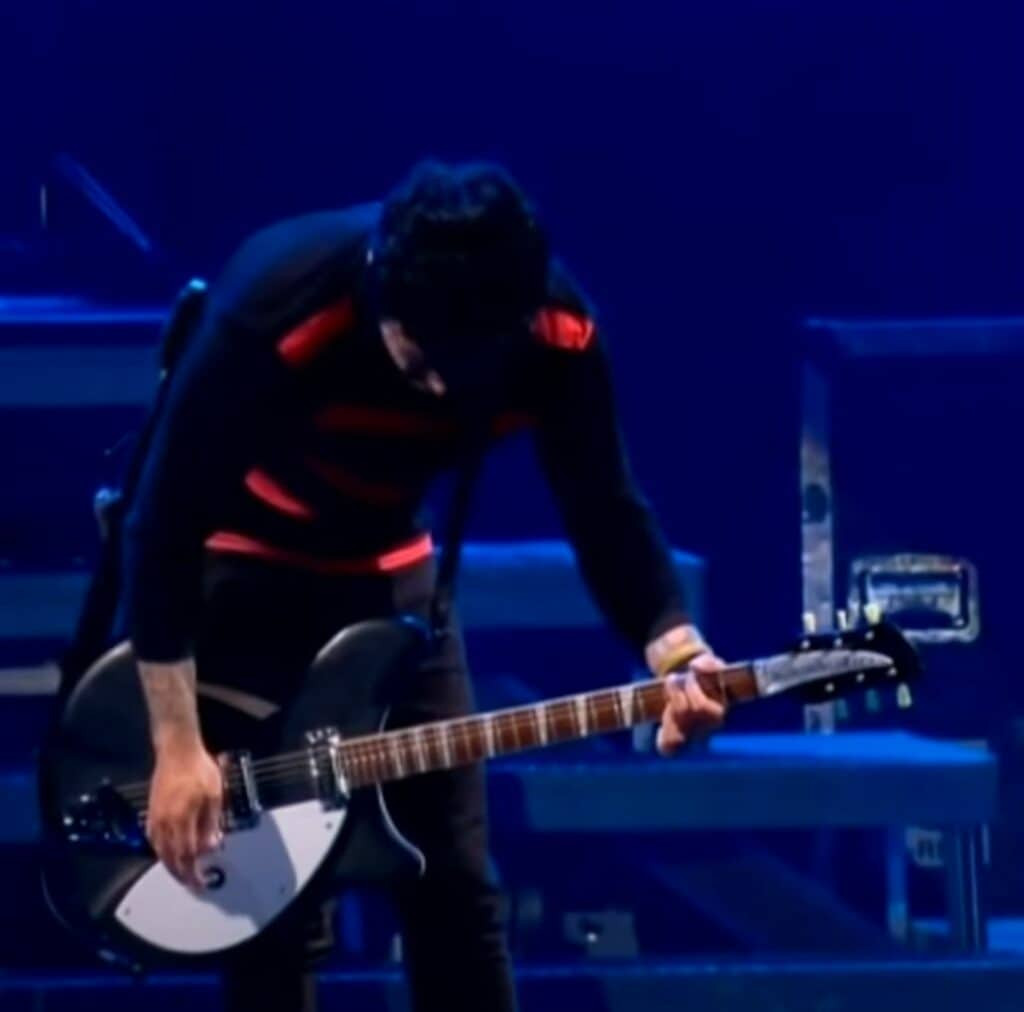 Billie Joe Armstrong playing his black Rickenbacker 360 guitar, known for its distinctive jangle and chime.