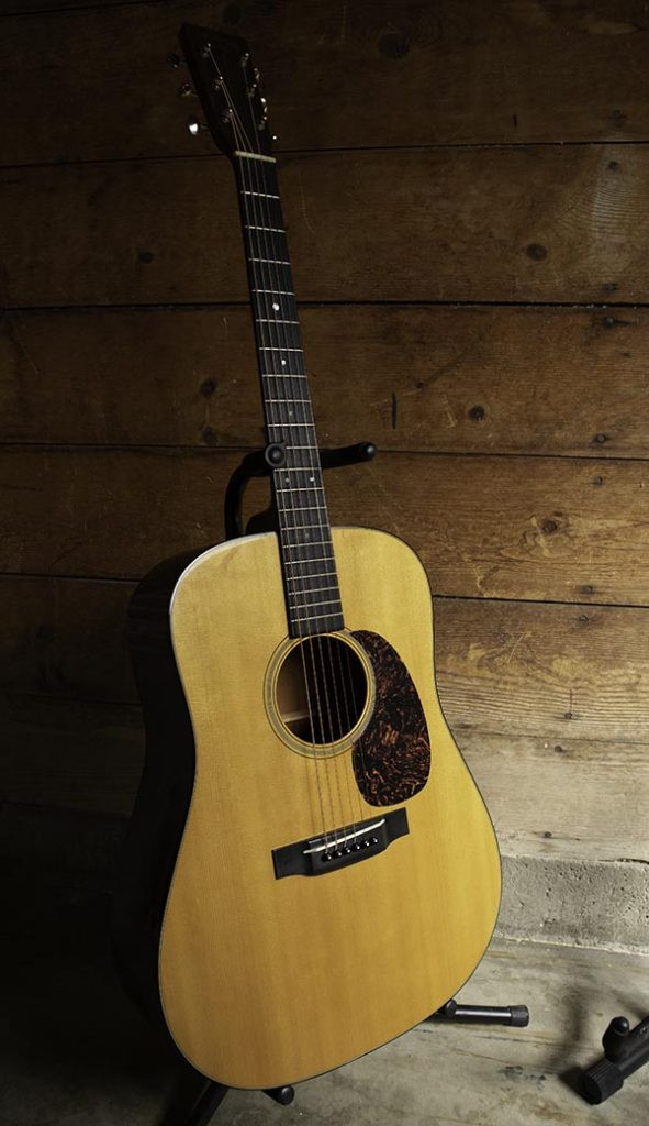 Acoustic guitar on a floor stand in a room