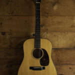 Acoustic guitar hanging on a wall hanger in a room