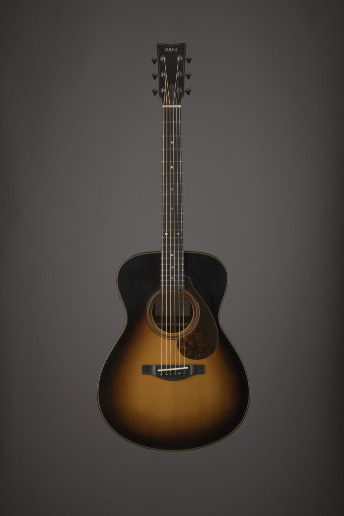 David Ryan Harris playing his custom Yamaha acoustic guitar, showcasing its tobacco burst finish and body shape
