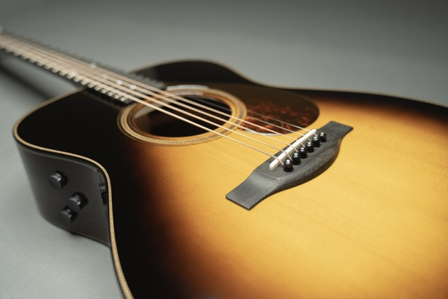 David Ryan Harris discussing design details with Yamaha luthiers, focusing on the guitar's features and aesthetics