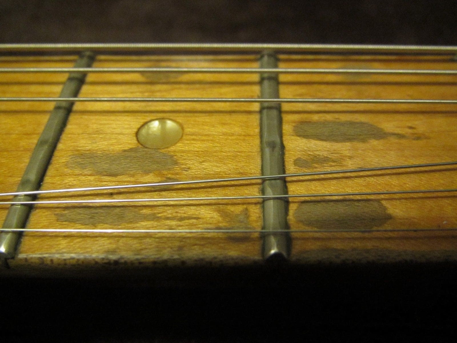 Close-up of the Gibson L6-S fingerboard, highlighting the simple dot inlays on a maple neck, contributing to its clean and functional design aesthetic favored by some players.