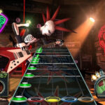 Guitar Hero gameplay featuring colored note tracks on screen, illustrating the rhythm game experience.