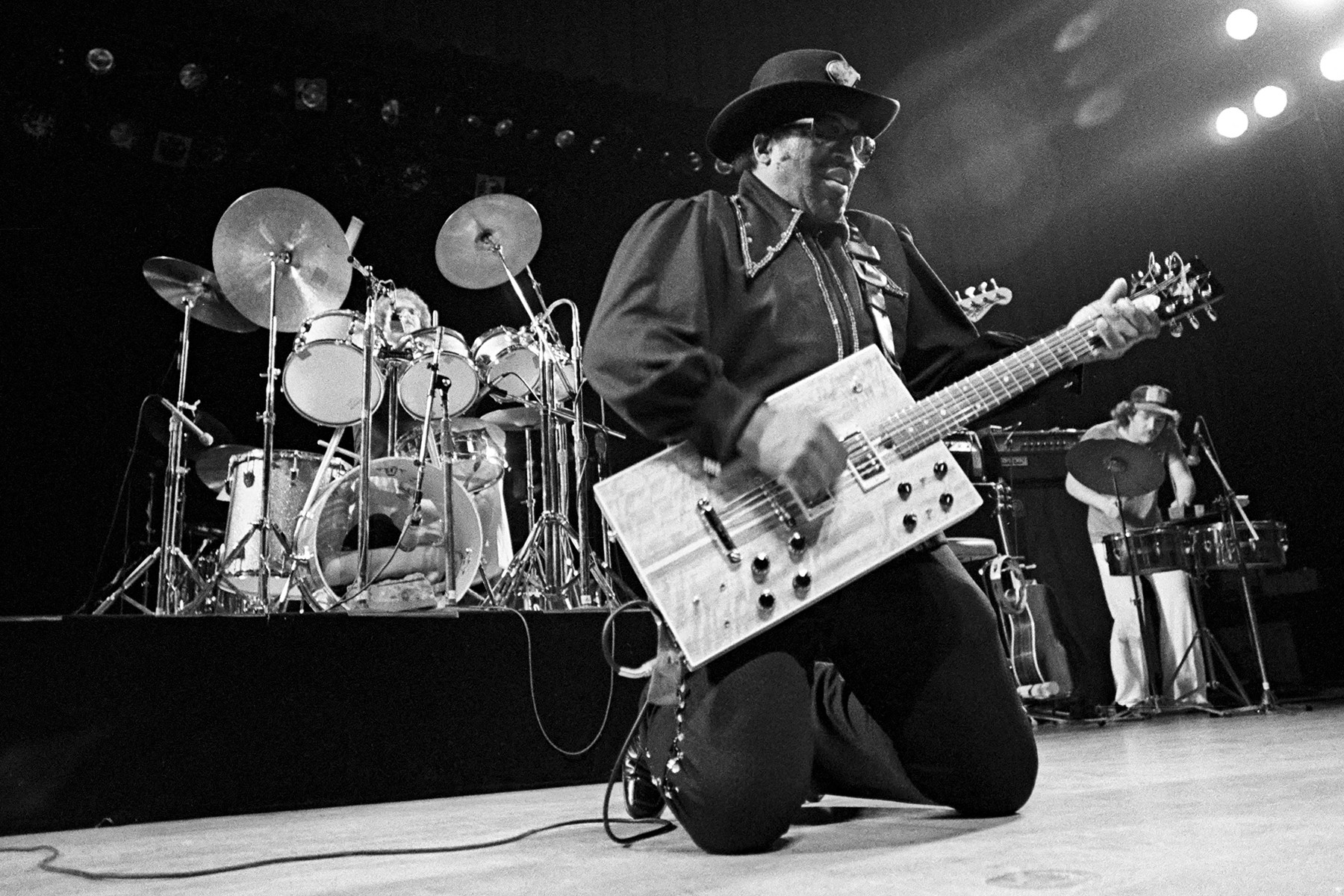 Bo Diddley performing with his signature rectangular guitar, pioneering his iconic beat and stage presence