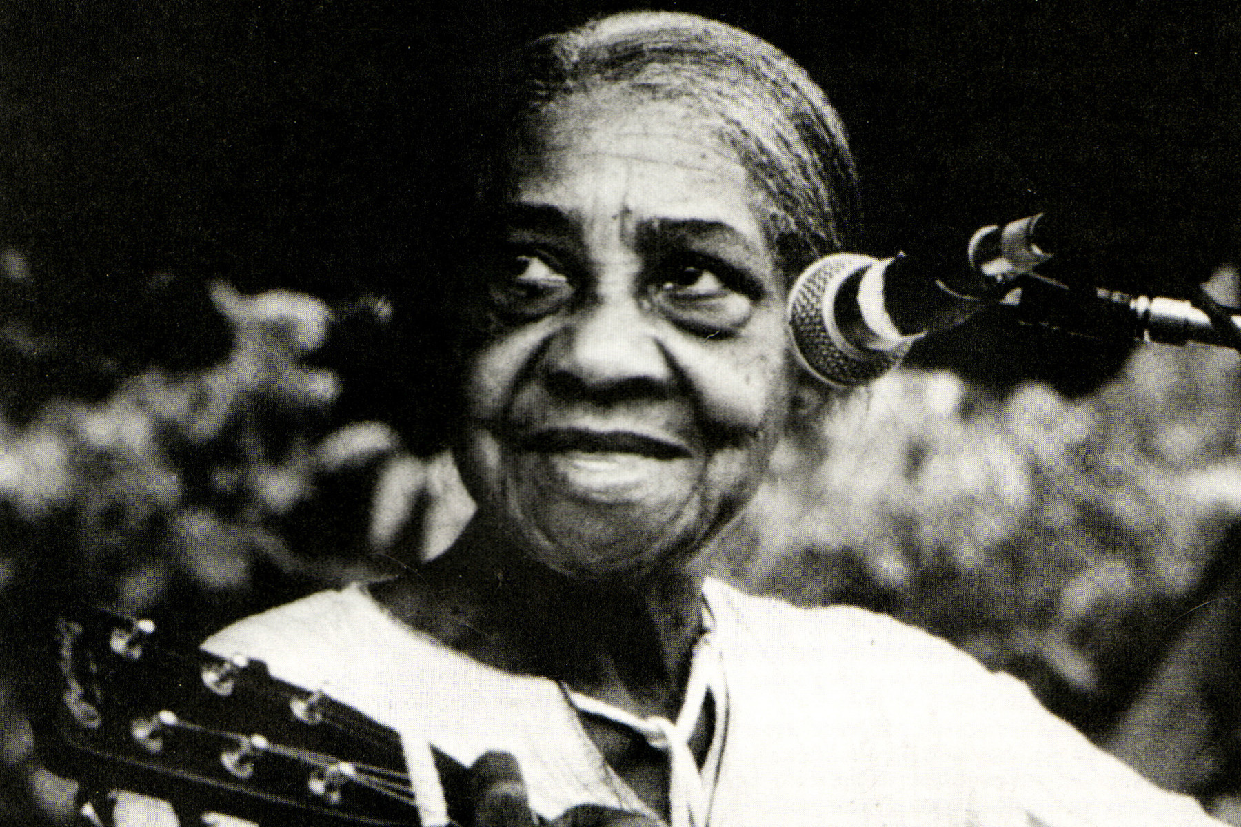 Elizabeth Cotten playing guitar, showcasing her unique upside-down left-handed style and fingerpicking technique