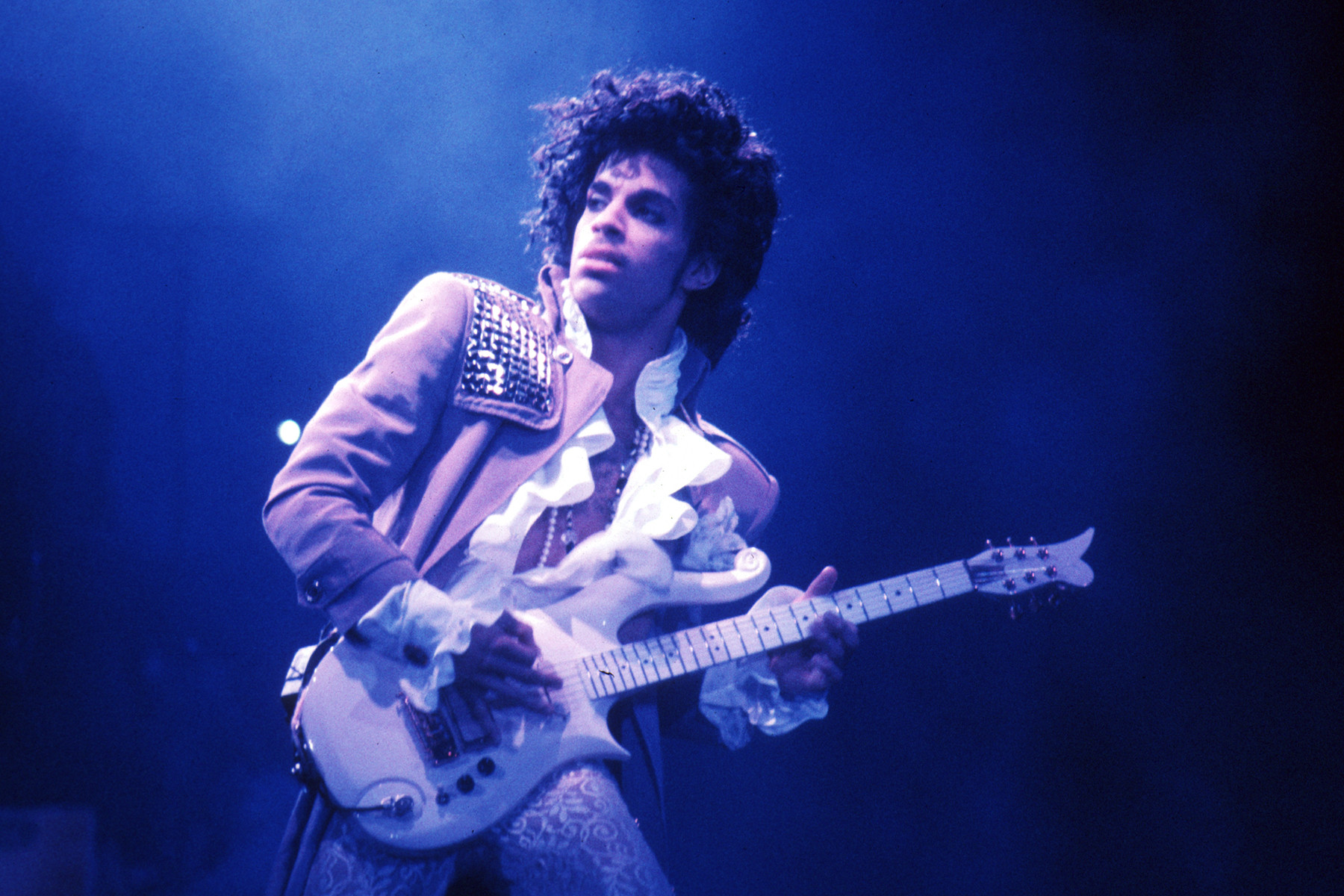 Prince performing in Inglewood, 1985, showcasing his virtuosic guitar playing and his flamboyant stage persona