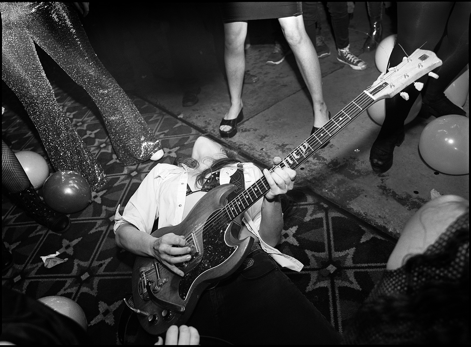 Black and white photo of woman bending over backwards while playing electric guitar