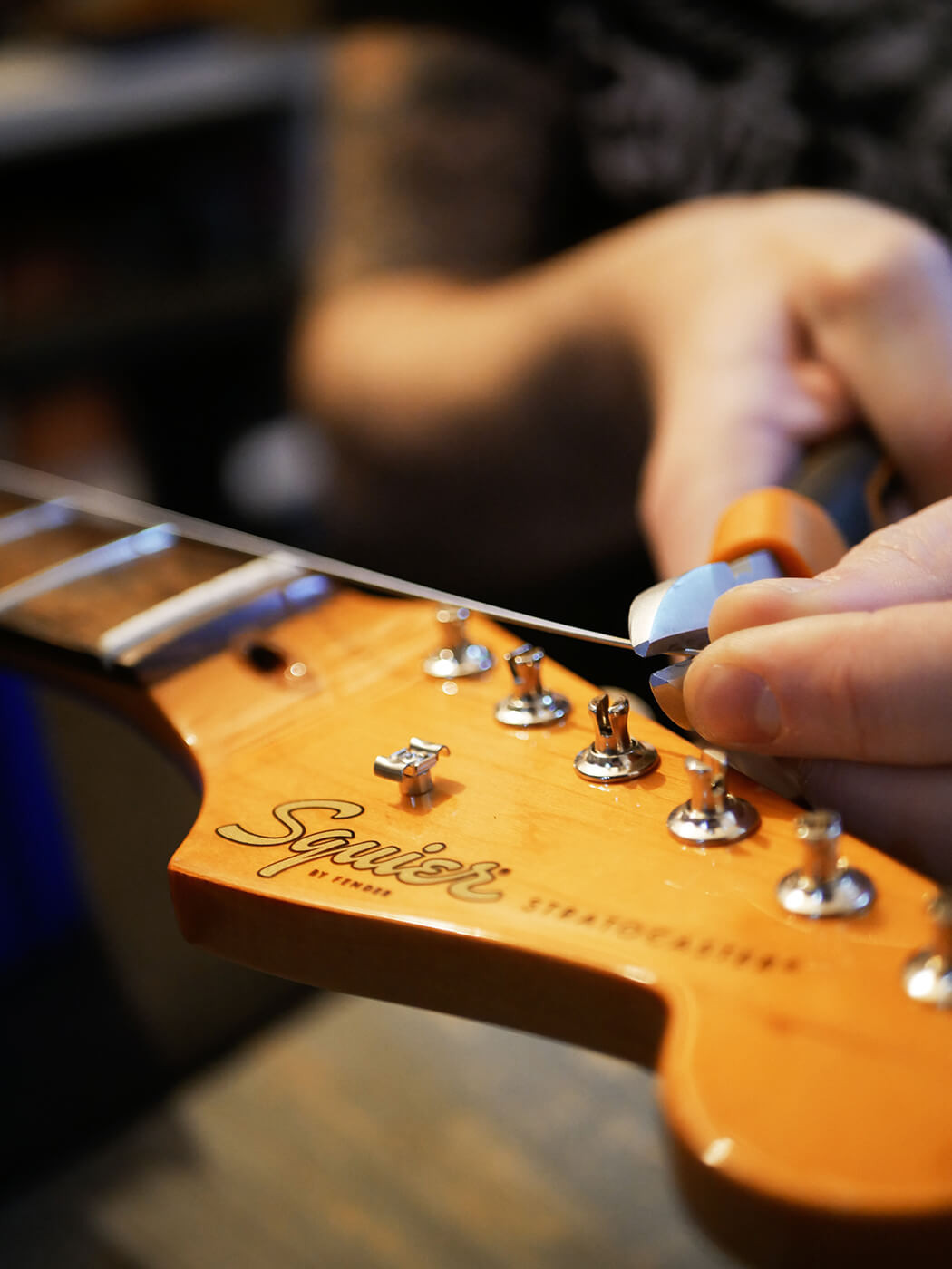 Adjusting tremolo springs on the back of a guitar, demonstrating a key step in how to set up a guitar for improved tuning stability.