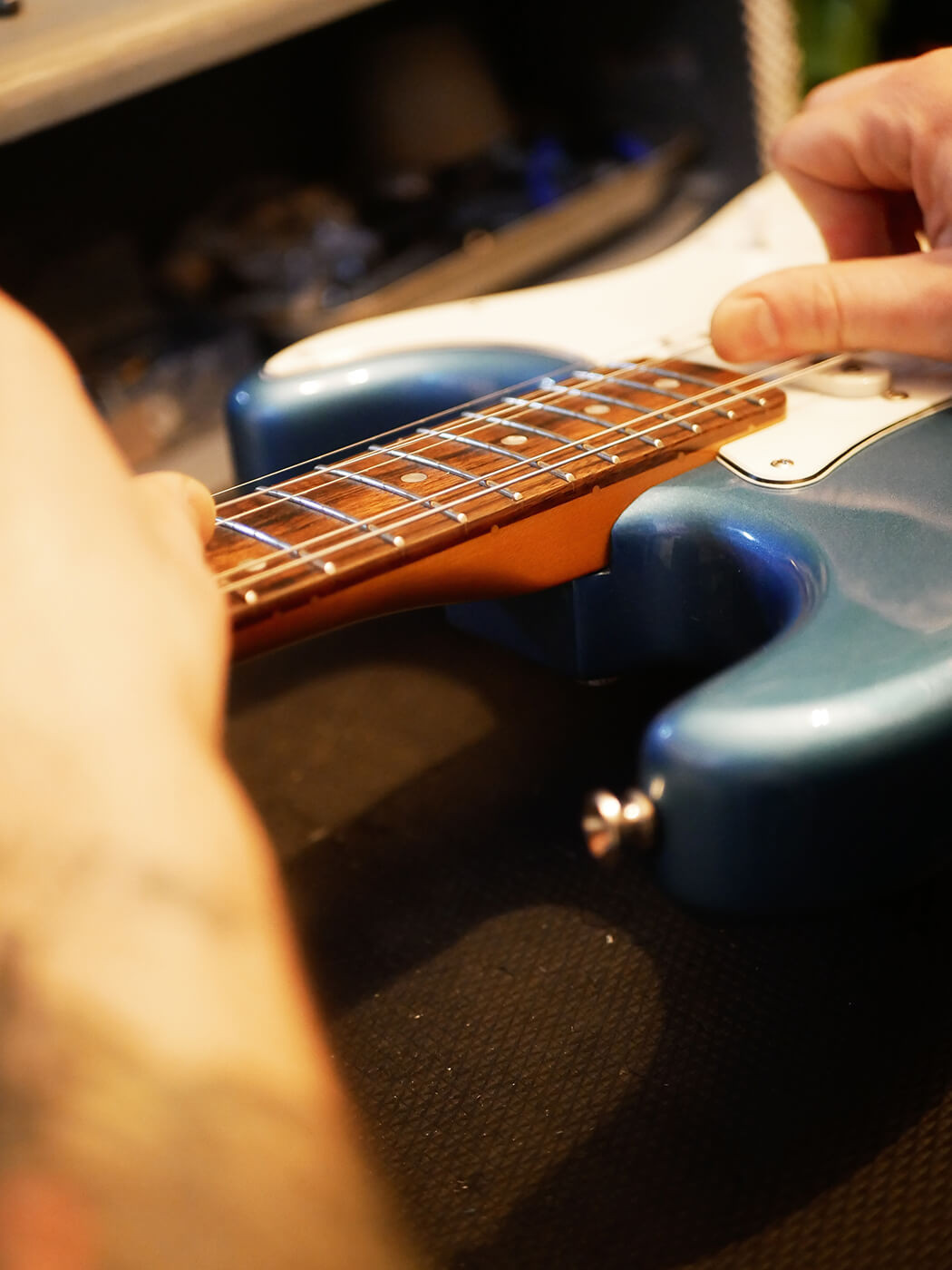 Restringing a guitar by threading strings through the bridge, showing the process of putting on new strings in how to set up a guitar.