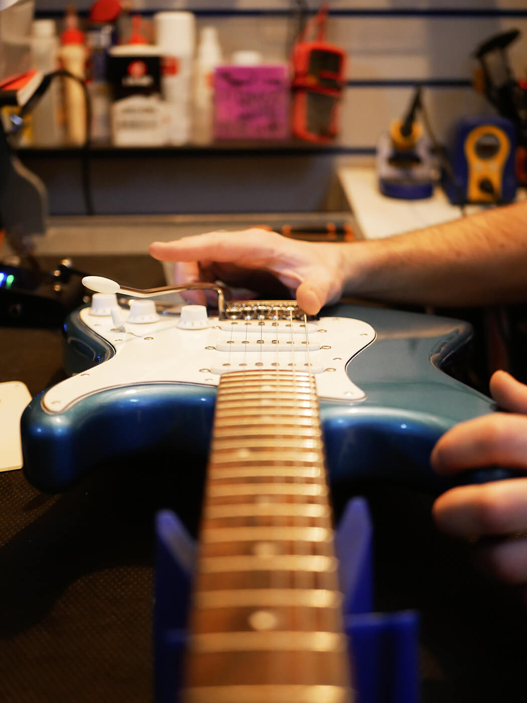 Tuning guitar strings on the headstock, illustrating the final stage of restringing a guitar as part of learning how to set up a guitar.