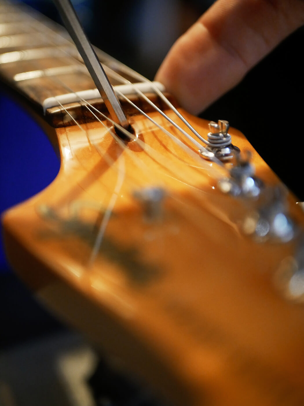 Sighting down the guitar neck to check for relief, demonstrating how to assess neck straightness in the process of how to set up a guitar.