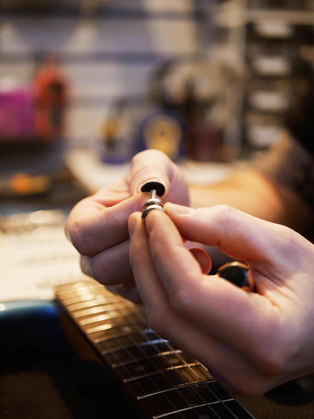 Adjusting bridge saddles on a guitar, showing the string height adjustment step in learning how to set up a guitar for optimal action.