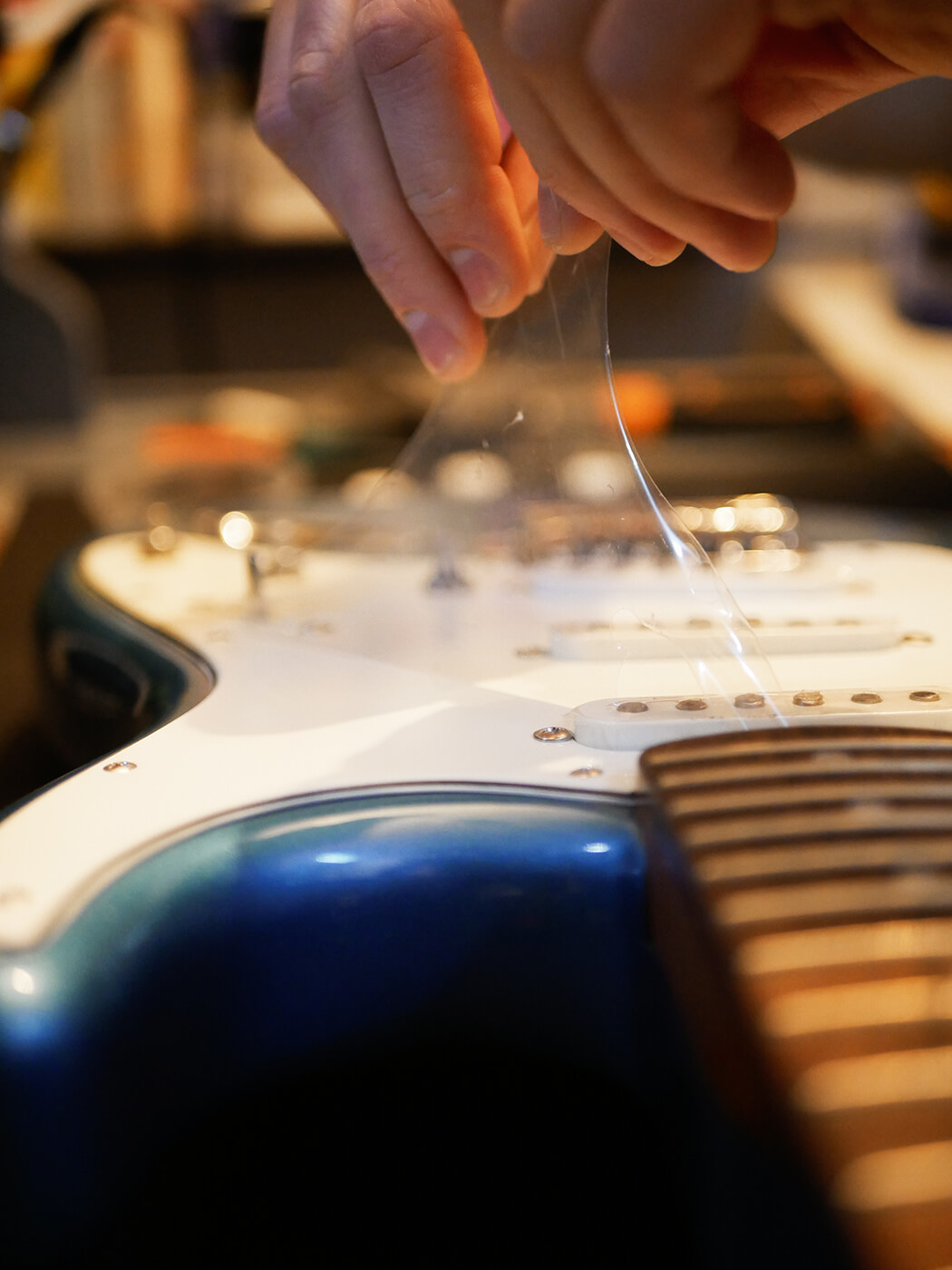 Close-up of removing guitar strings from the bridge, showing a detail in the process of how to set up a guitar, specifically string removal.