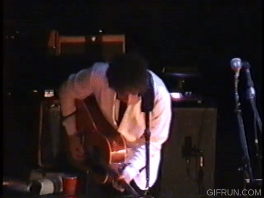 Bob Dylan in the zone dance guitar pose looking at shoes