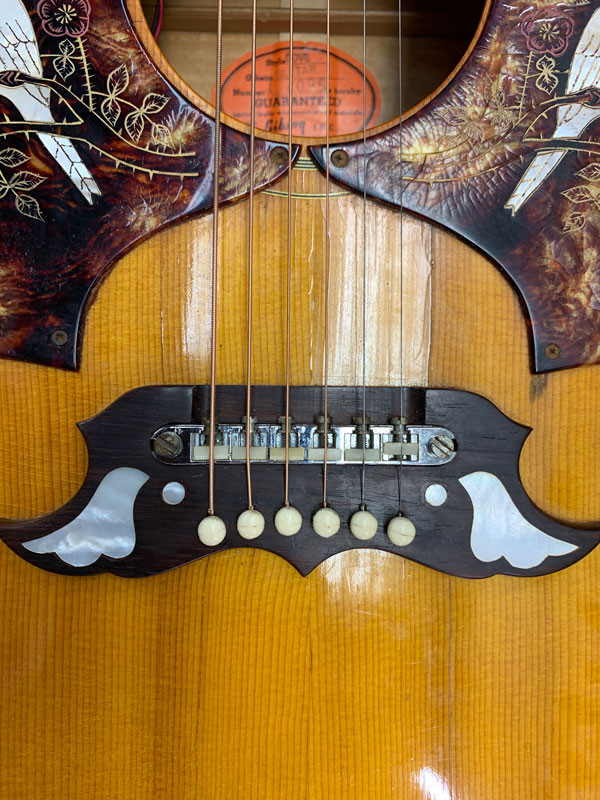 Original saddles being carefully reinstalled on the Gibson Dove