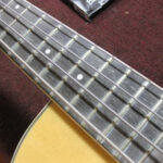 Close-up of the Ovation bass fretboard before defretting, showing a dirty and uneven surface