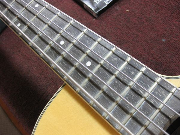 Close-up of the Ovation bass fretboard before defretting, showing a dirty and uneven surface