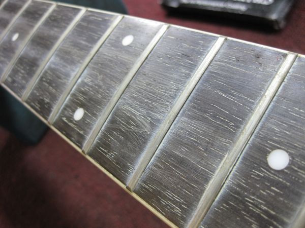 Another angle of the worn fretboard highlighting the need for cleaning and restoration before conversion