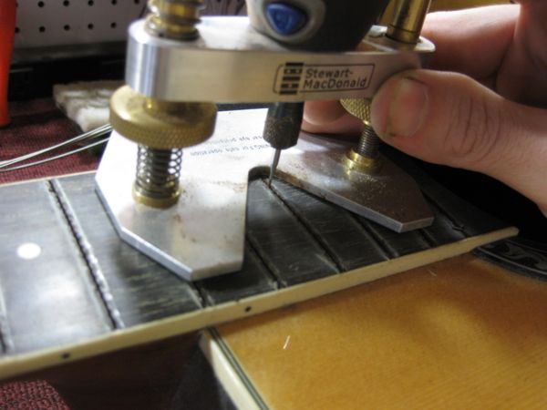 Close up view of the Dremel bit precisely cleaning the bass fret slots
