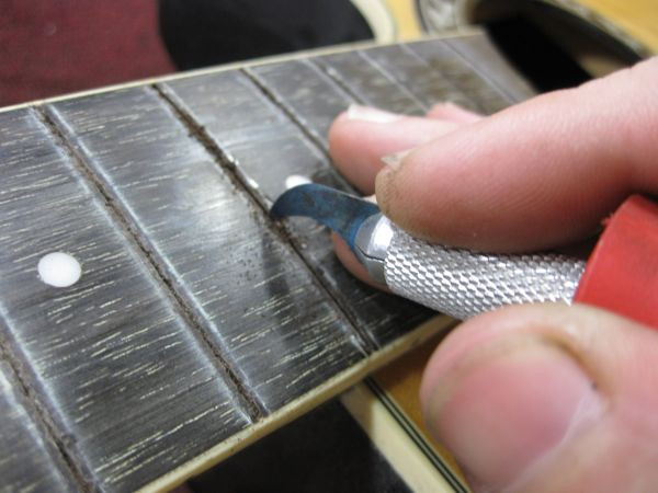 Cleaning the fret slots with a brush to remove debris after routing