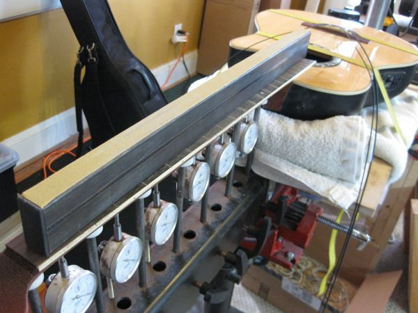 Using a leveling beam and sandpaper to level the fretless bass fretboard on a neck jig