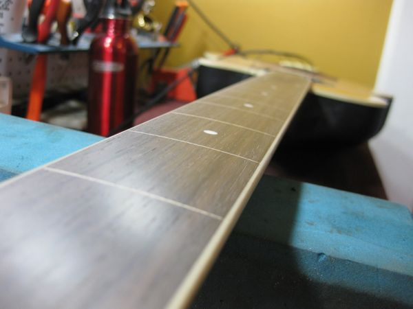 The leveled rosewood fretboard after sanding, showing a smooth, even surface ready for finishing