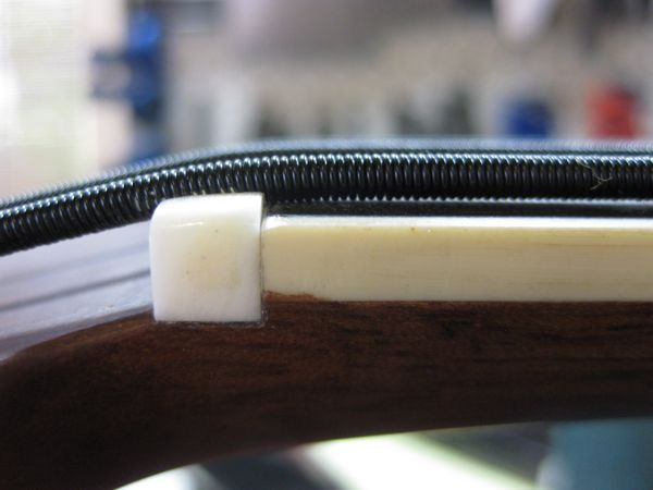 Side view of the bass headstock and nut, highlighting the low string action at the nut