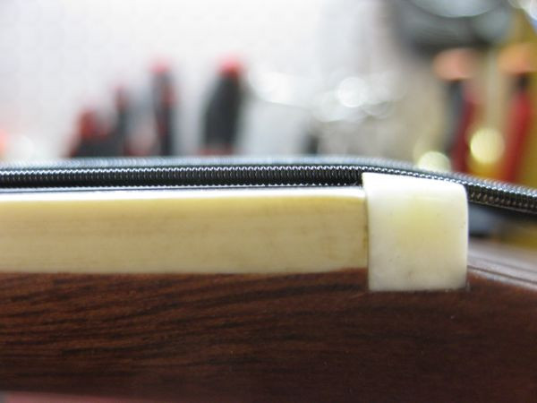 Close-up of the newly crafted bone nut, showing a very low string height for optimal fretless playability