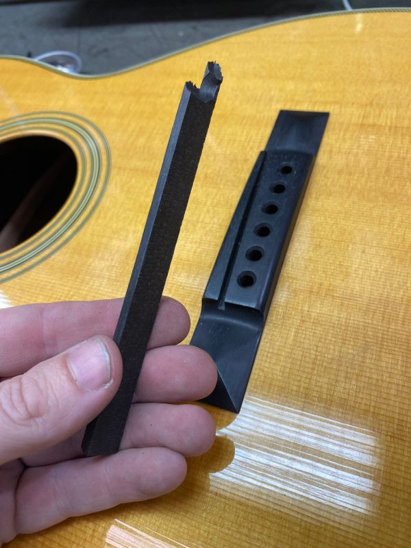 Ebony being glued into the saddle slot of the acoustic guitar bridge