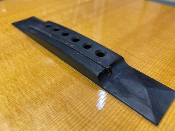 Close up of the filled saddle slot on the acoustic guitar bridge