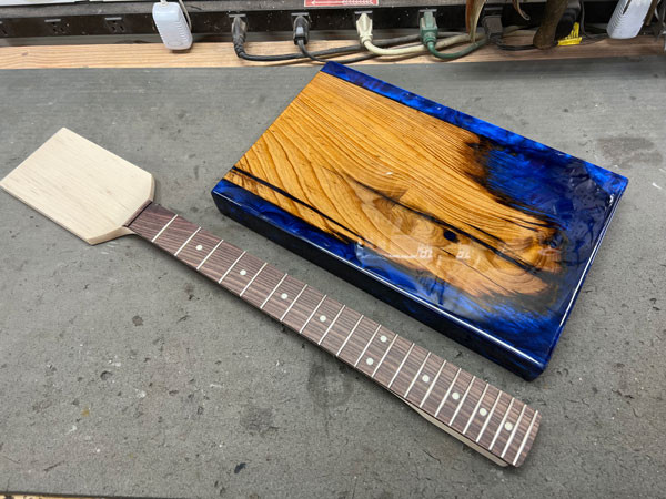 Close up shot of the epoxy block guitar body, showing pencil lines marking the centerline and scale length for precise instrument construction.