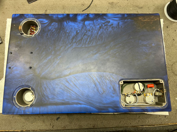 Detailed view of the guitar's wiring process, showing the careful soldering and connection of electronic components within the guitar body.