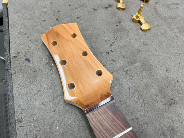 Headstock after finishing with clear lacquer, achieving a shine that complements the guitar body and enhances the wood grain.