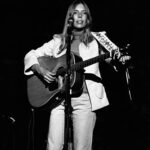 Joni Mitchell onstage with acoustic guitar