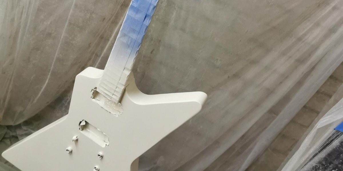 Guitar kit build painting process showing the guitar body being spray painted in a garage setup