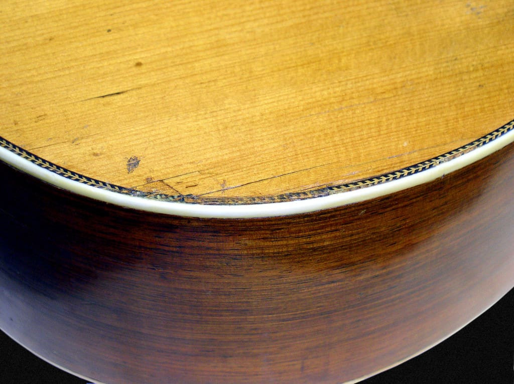 A detailed shot of the lower bout repairs on Tony Rice's 1935 D-28, showcasing the herringbone inlay