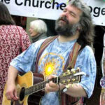 Malcolm Guite playfully imitates Jerry Garcia, highlighting his diverse interests from theology and poetry to music, reflecting his engaging and approachable personality.