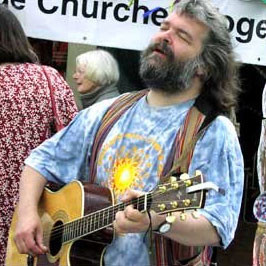 Malcolm Guite playfully imitates Jerry Garcia, highlighting his diverse interests from theology and poetry to music, reflecting his engaging and approachable personality.