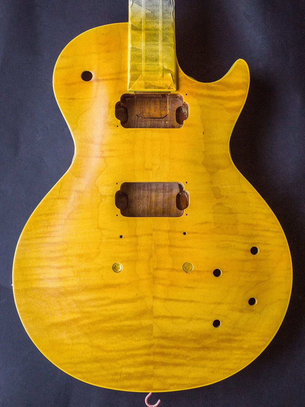 After achieving a level surface with cellulose sanding sealer, the bursting process begins with two coats of aniline yellow
